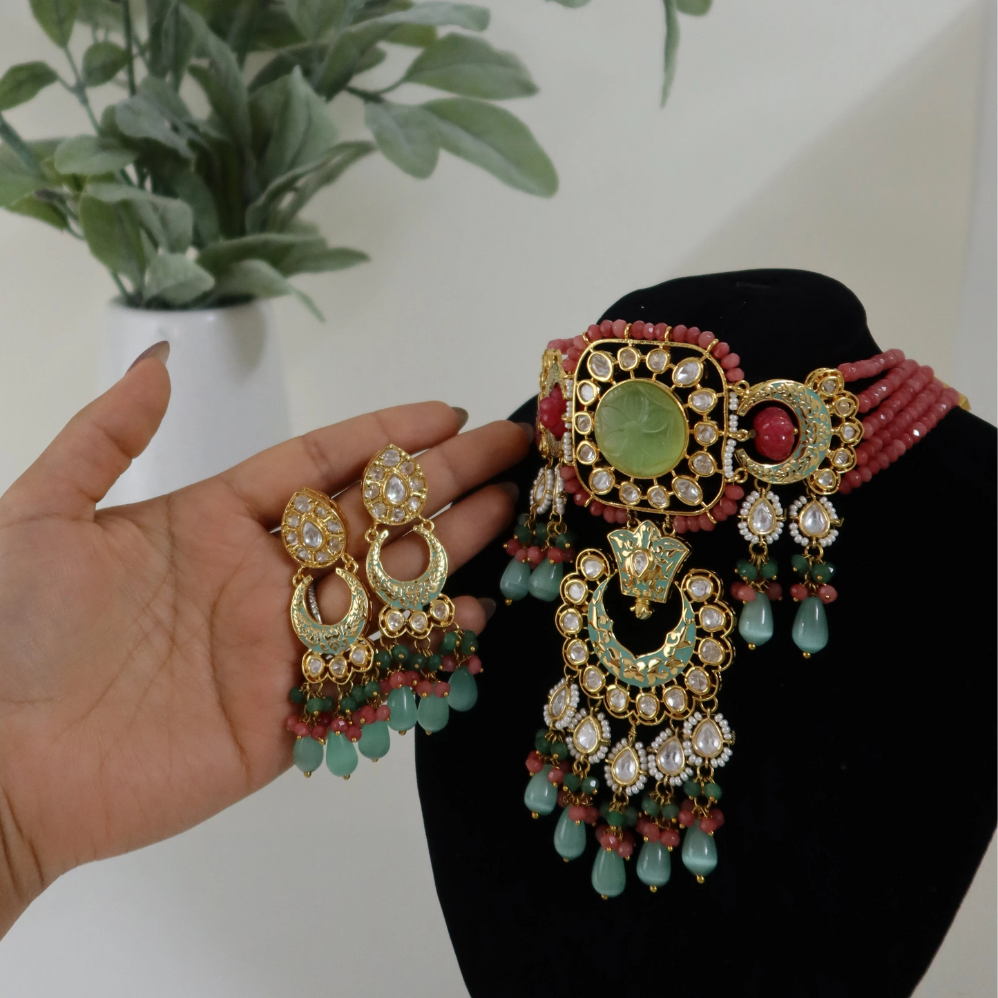 Traditional earrings held by a hand with a plant in the background