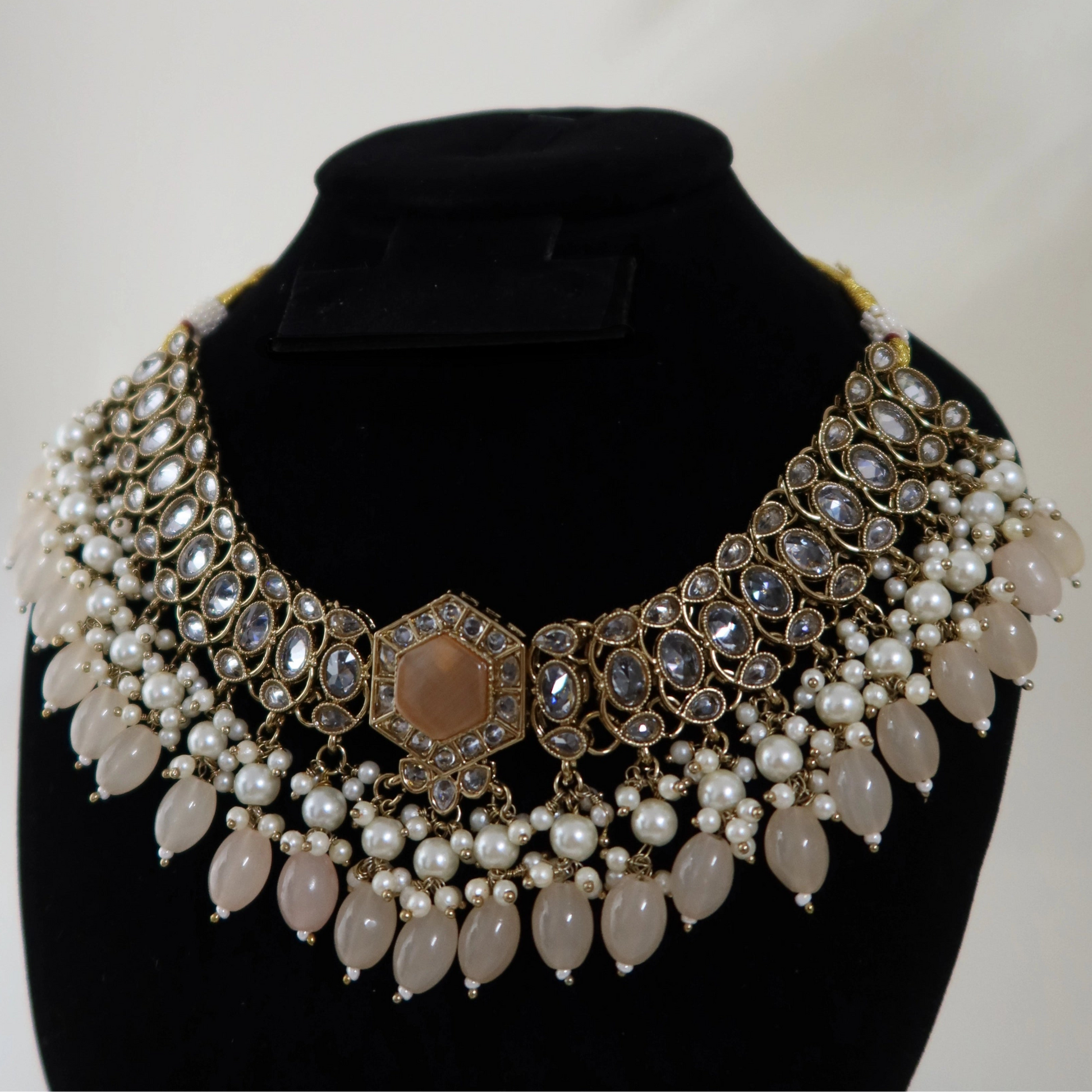 Decorative necklace with pearls and crystals on a black mannequin bust against a white background