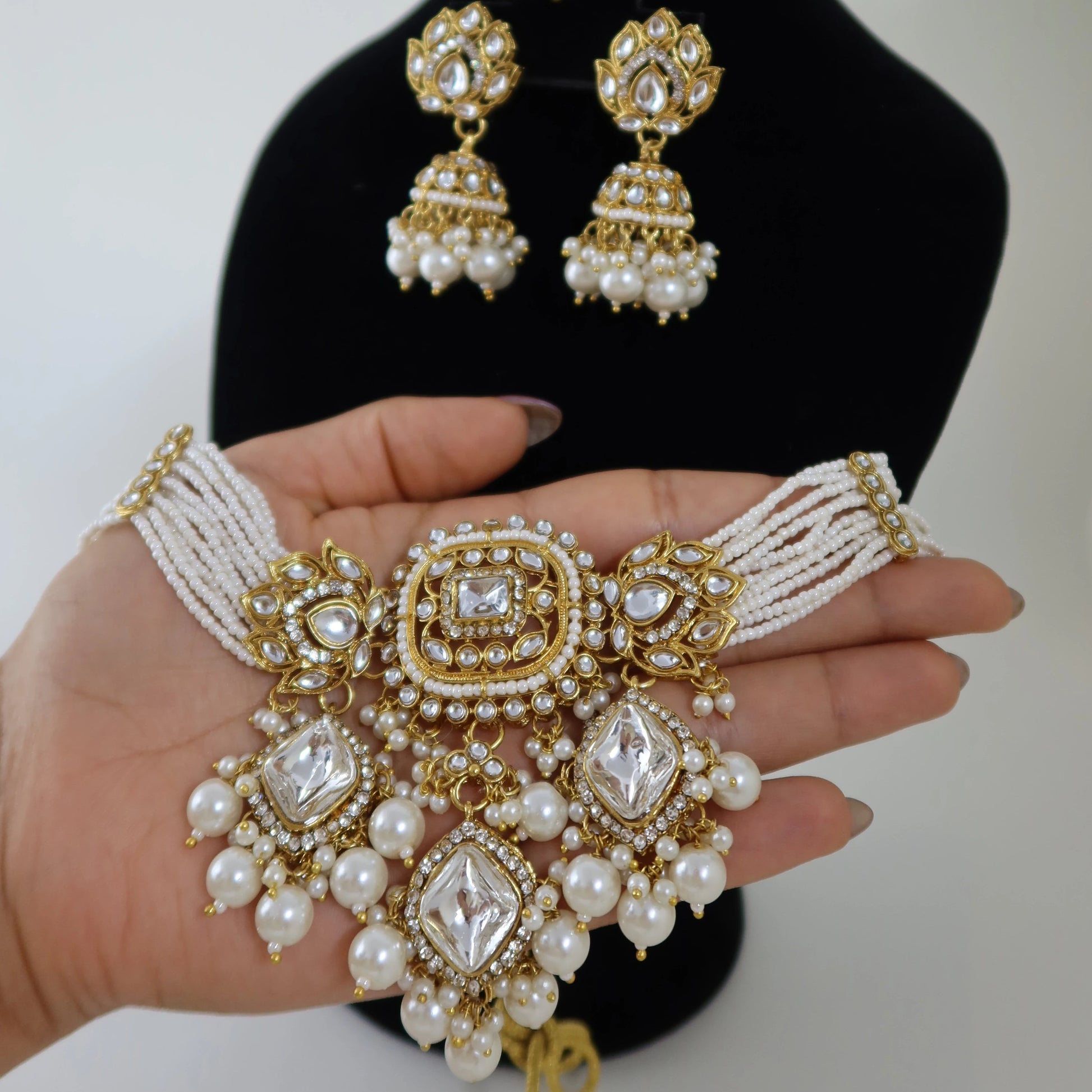 Gold and pearl jewelry set including necklace, earrings, and bracelet on a white background.