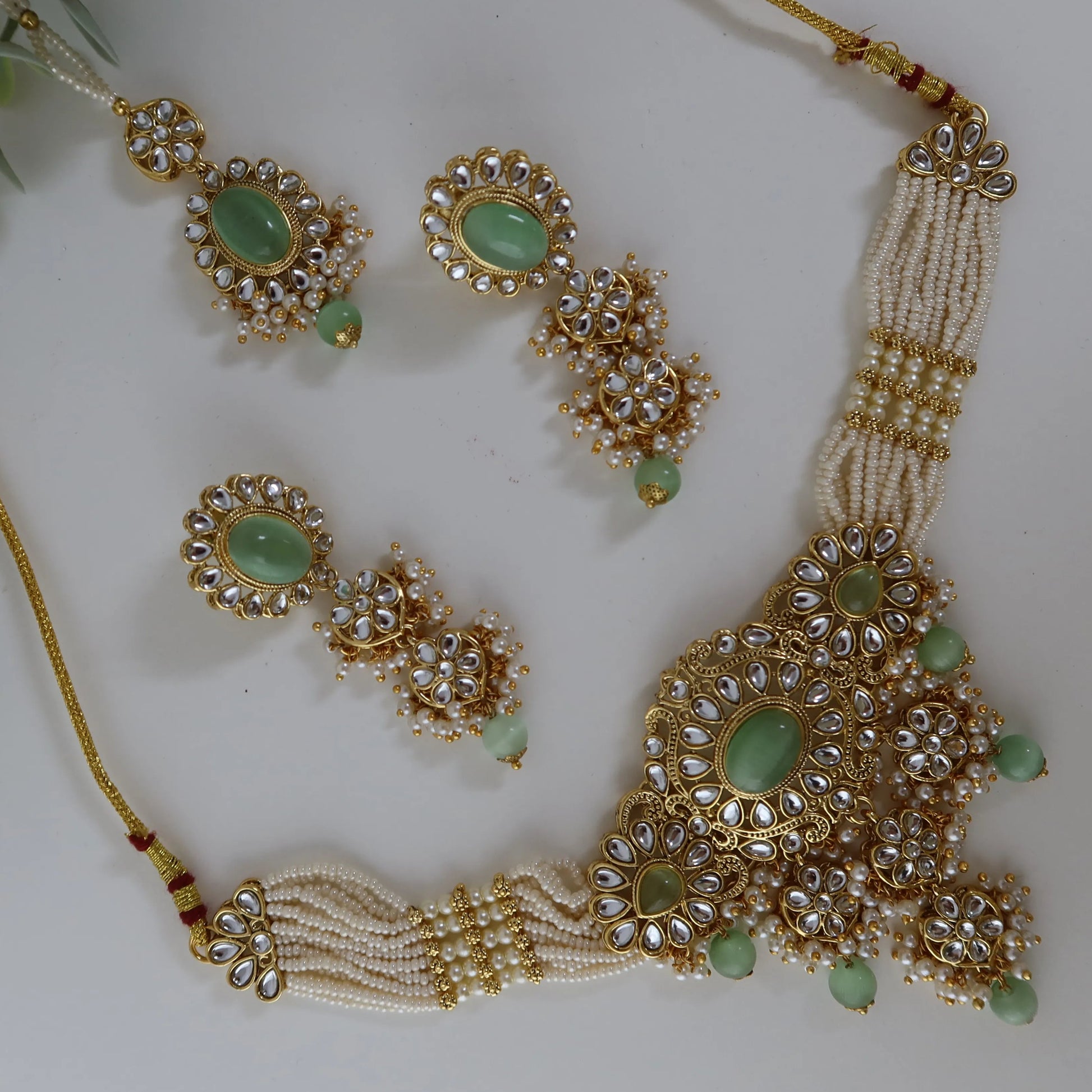 Gold and green jewelry set with leaves on a white background