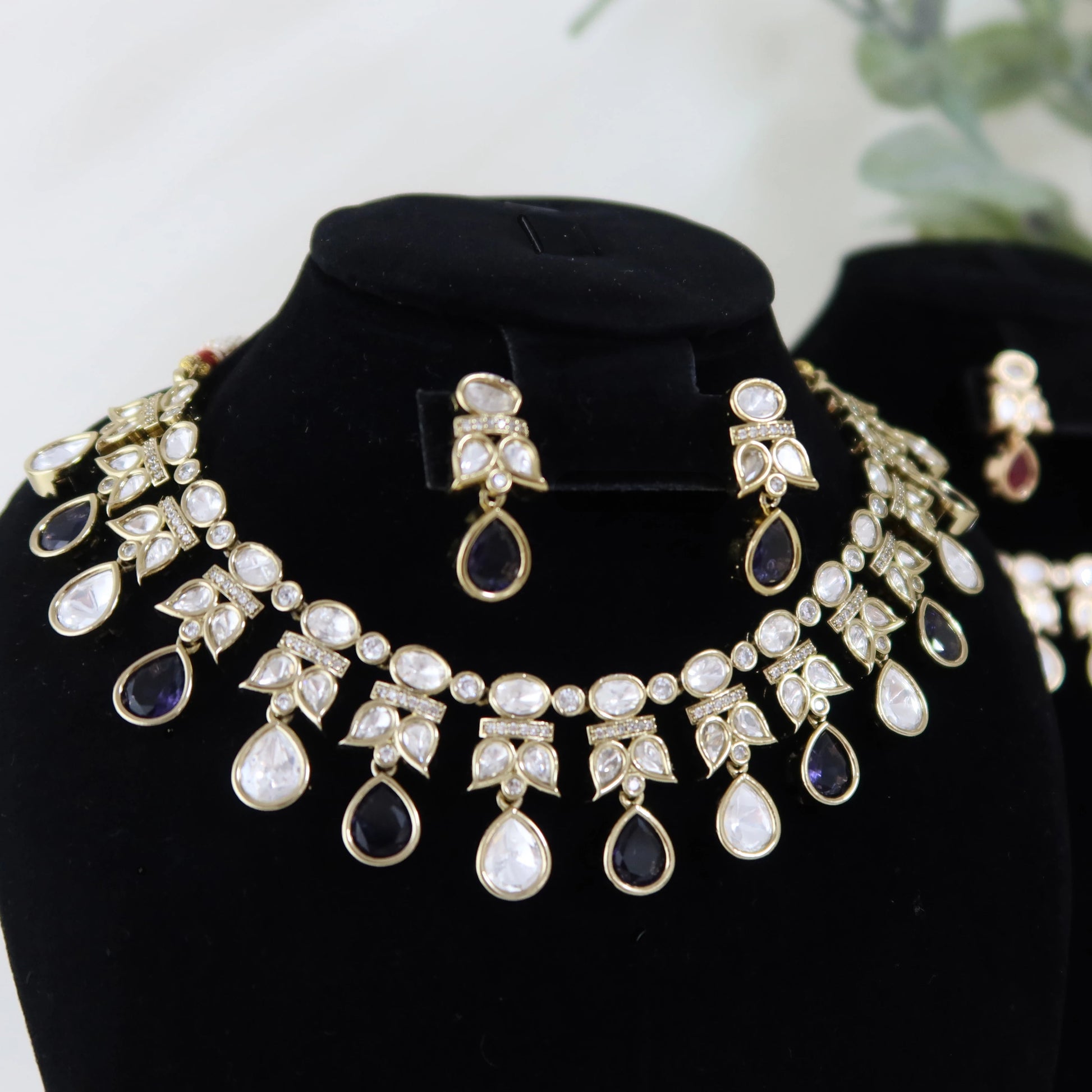 Jewelry set including a necklace and earrings on a black stand with a white background.