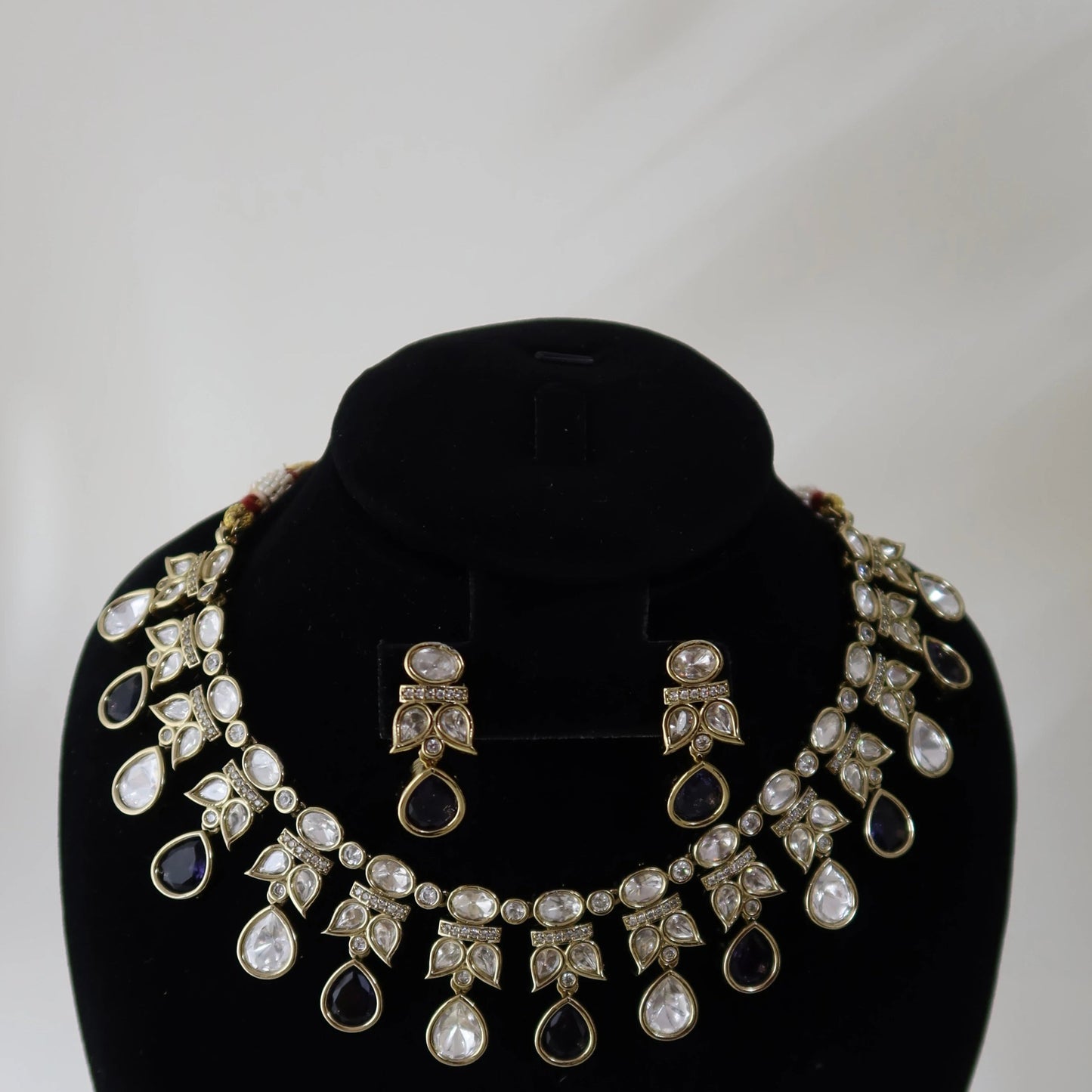 Necklace and earrings set on a black velvet stand with a white background