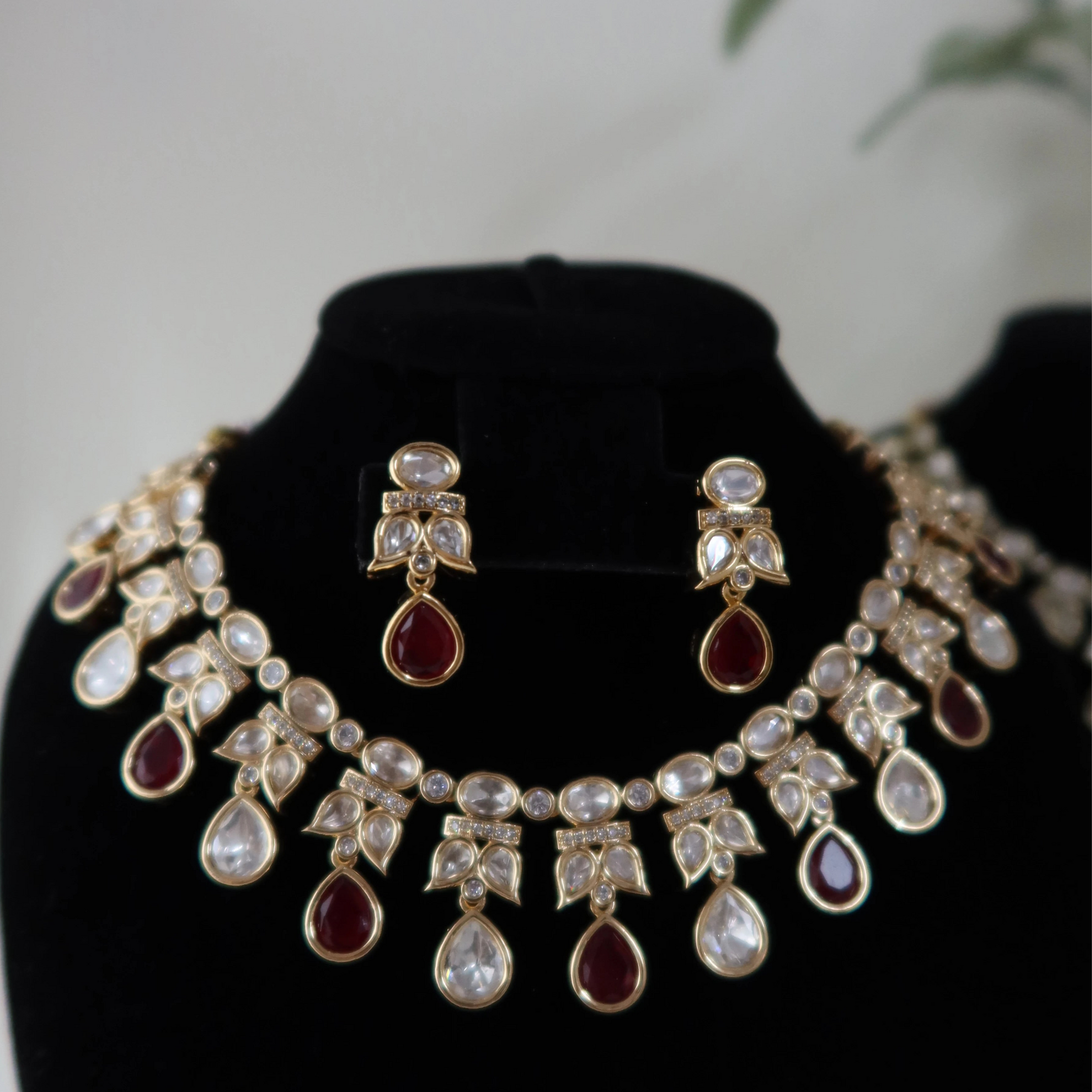 Jewelry set with necklace and earrings on a black stand against a light background