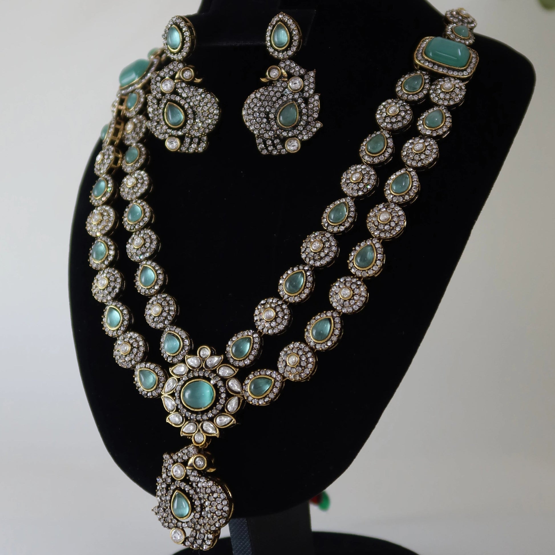 Turquoise and silver jewelry set on a black stand with a white background