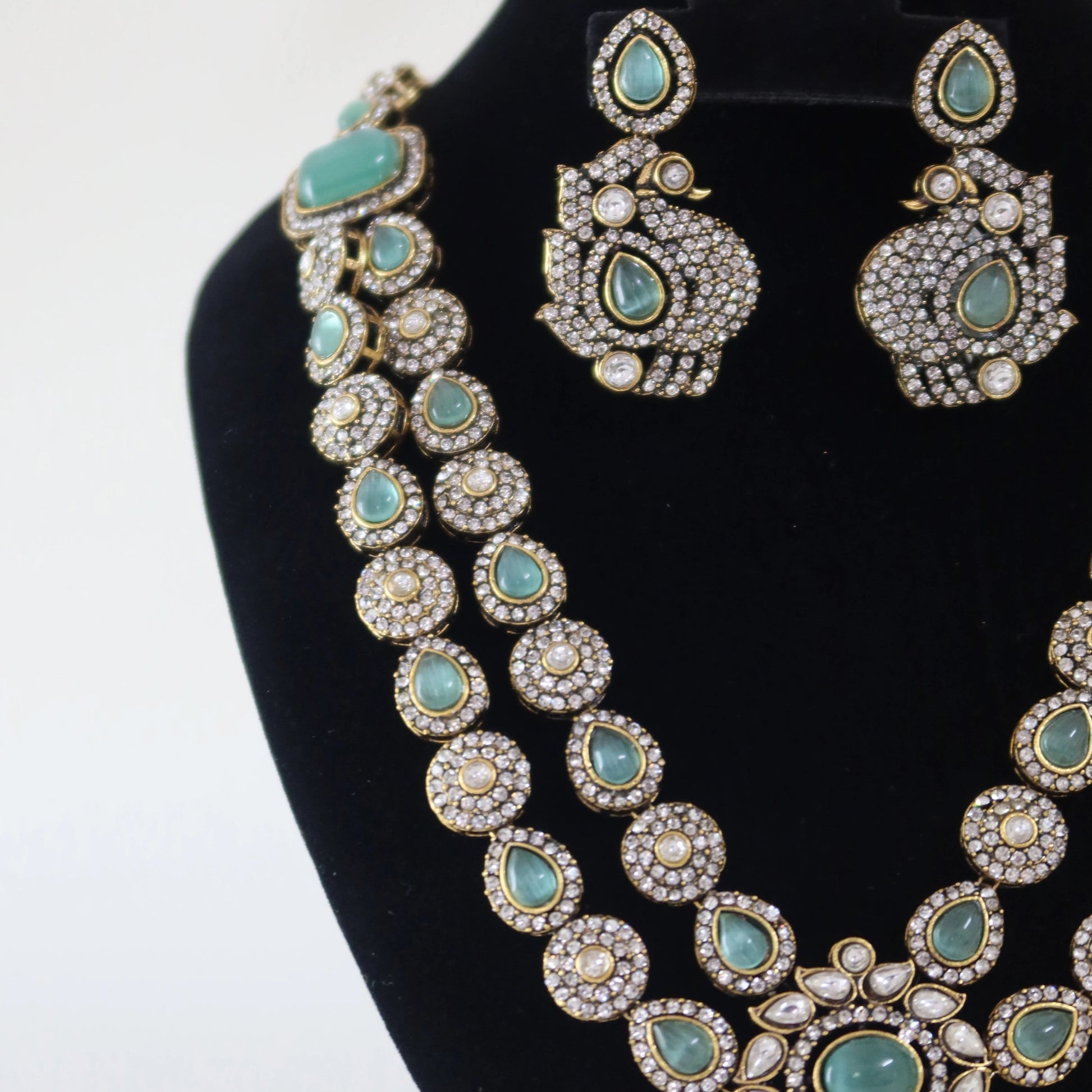 Turquoise and silver necklace set on a black stand with a white background