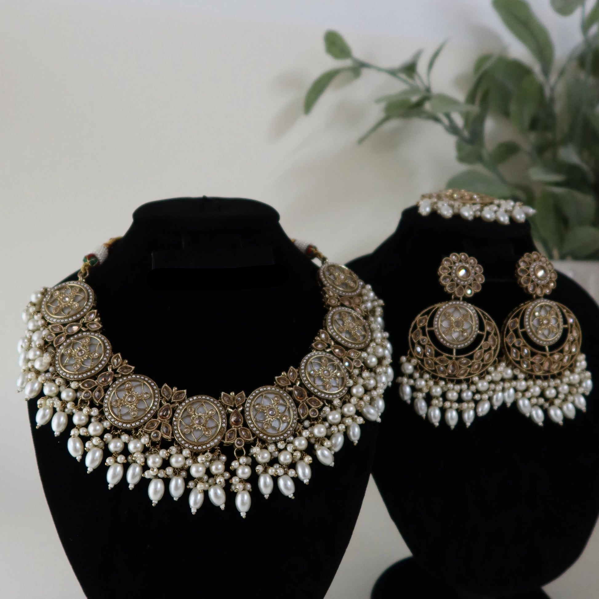 Jewelry set including a necklace and earrings on black stands with a white background.